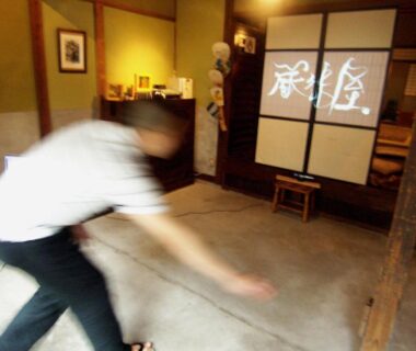 Genkan with shoji screens, wooden beams and blurred staff movement at Itsumoya in Hiroshima