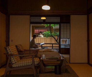 Traditional tatami room with low table, wicker chairs, shoji screens opening to a small courtyard garden