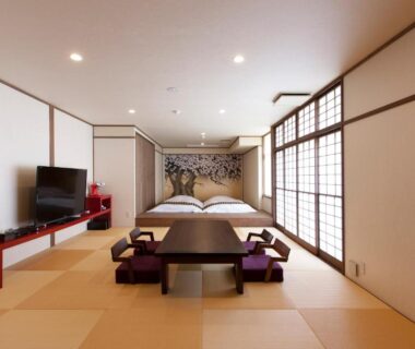 Tatami mat room with low table, floor cushions, two beds and shoji screens at Iwaiyado Jyuan Nikko Kawaji