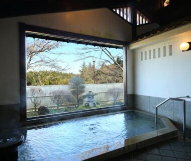 Indoor onsen bath with large window overlooking garden and trees at Iwamura Sanso in Gifu