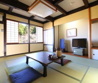 Traditional tatami room with low table, zabuton cushions, shoji screens and garden view at Iwamura Sanso, Gifu