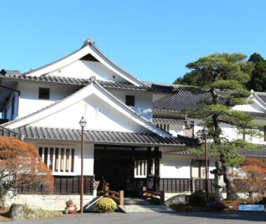 Traditional exterior with tiled roof, entrance, and pine trees at Iwamura Sanso in Gifu, Chūbu