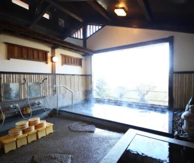 Stone indoor onsen bath with wooden stools and wide window view at Iwamura Sanso, Chūbu Gifu Japan