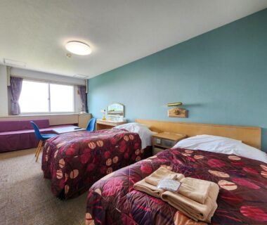 Twin beds with folded towels in Iwanai Kogen Hotel guest room, Hokkaidō, Japan