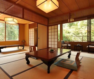 Traditional tatami room with low wooden table, zabuton cushions, shoji screens and green garden views at Iwaso in Hiroshima