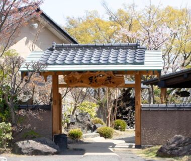 Wooden entrance gate with tiled roof and stone path at Iyashi no Yado Iroha in Ōita, Kyūshū