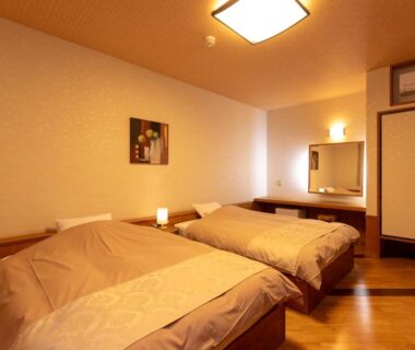 Twin beds, wooden floor, sliding closet doors and vanity at Iyashi no Yado Iroha, Ōita, Kyūshū