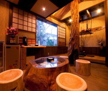 Indoor wooden soaking tub with stump stools, shoji screens and rustic timber interior at Iyashi no Yado Iroha, Ōita