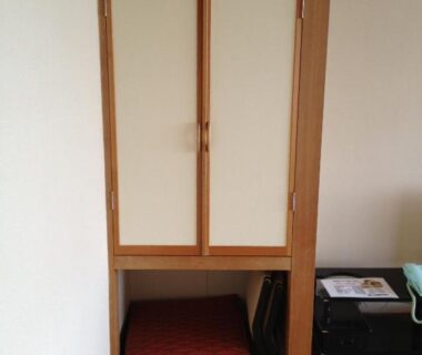 Sliding closet with folded futon and cushions on tatami beside a suitcase