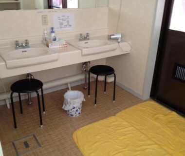 Wash area with twin sinks, stools and floor bedding at Iyashinoyado Rodem in Iwate