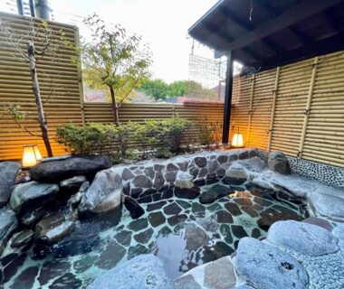 Outdoor stone onsen bath with bamboo fence and lanterns at Izu Katsura no Izumi Onsen, Shizuoka