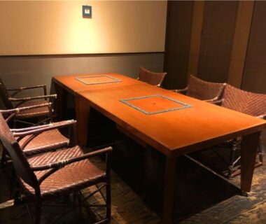 Wooden dining table with inlaid panels and woven chairs in intimate dining room at Izu Katsura no Izumi Onsen