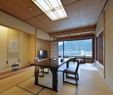 Traditional tatami room with low table, shoji screens and large window overlooking coastal scenery in Shizuoka
