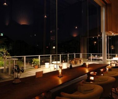 Glass-front lounge with low seating and candlelit counter overlooking garden at Izu-Nagaoka Hotel Tenbo Shizuoka