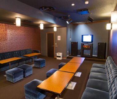 Karaoke room with long sofas, low tables and television at Izu Nagaoka Kinjokan in Shizuoka