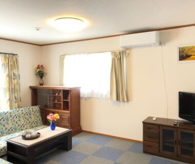 Sofa and coffee table with flowers in a bright room at Izu Shirada Villa, Shizuoka
