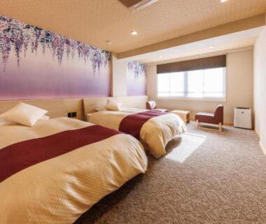 Three low beds with purple floral wall art at Izu Atagawa Yubana Mankai, Shizuoka ryokan room