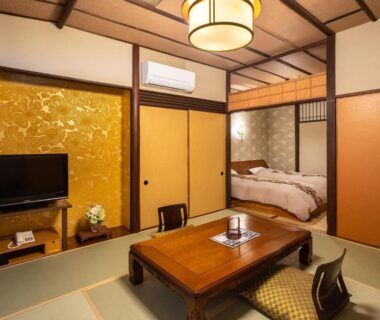 Tatami room with low table, sliding shoji screens and beds at Izu atagawa Yubana mankai, Shizuoka