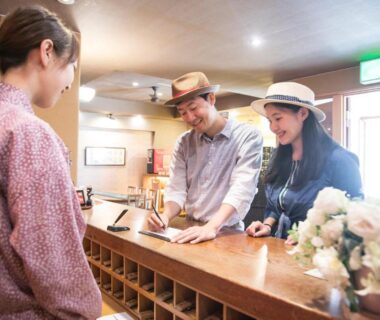 Guests checking in at wooden reception counter with staff in patterned kimono and cubbyholes