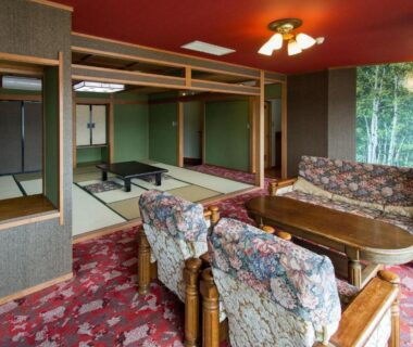Spacious tatami seating area with low table and floral upholstered sofas at Izuito Onsen Daitokan in Shizuoka