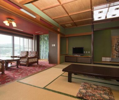 Tatami floored room with low table and seating by window at Izuito Onsen Daitokan in Shizuoka