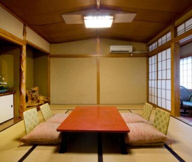 Traditional tatami room with low table, zabuton cushions, shoji screens and seating area at Izumi-so in Gifu