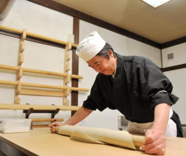 Ryokan chef in traditional attire rolling dough on wooden counter at Izumiya Zenbe in Nagano, Chūbu region