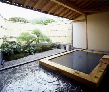 Wooden soaking tub on stone floor beside enclosed garden at Japanese Ryokan Seryo Kyoto