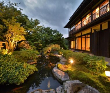 Lantern lit pond and stone path beside traditional wooden ryokan exterior at Ryokan Seryo Kyoto