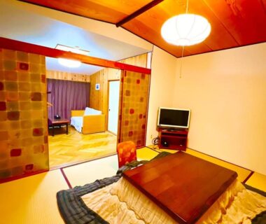 Traditional tatami room with kotatsu, low seating, sliding partitions and small TV at Morigen in Kyoto