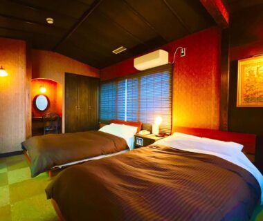 Warm twin bedroom with two beds, window blinds and wooden accents at Morigen ryokan in Kyoto