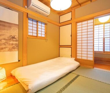 Traditional tatami room with futon, shoji screens, hanging scroll and soft lamp in Asakusa ryokan, Tokyo