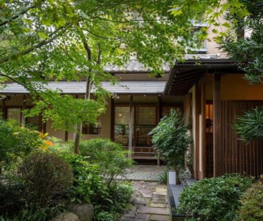 Stone path through lush green garden leading to wooden entrance of Jinya Ryokan Kanagawa