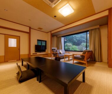 Spacious tatami room with low table, floor chairs, seating area and garden view at Jizaiso, Tochigi