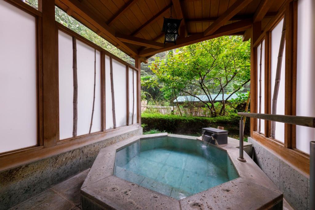 Stone onsen bath at Jizaiso Tochigi Stone soaking tub under wooden pavilion with shoji screens and garden view at Jizaiso, Kantō Tochigi