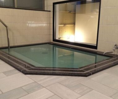 Tiled indoor onsen bath with steps and large interior window at Jizokan Matsuya Ryokan, Nagano