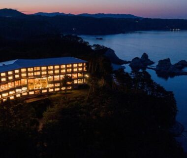 Evening exterior of illuminated ryokan overlooking rocky coastline near Jodogahama in Iwate, Tōhoku