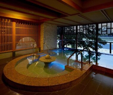 Circular stone onsen with wooden interior and snowy garden view at Juhachiro, Chūbu Gifu
