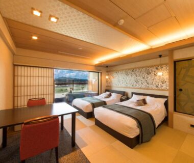 Tatami room with two beds, low table and shoji screens at Juhachiro in Gifu