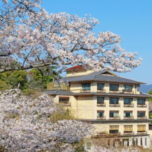 Blooming cherry trees framing Jukeiso ryokan building in Hiroshima, Chūgoku region
