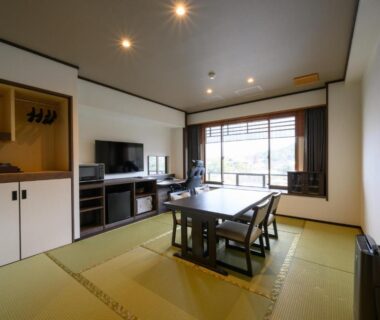 Tatami room with low table, chairs, TV and large window at Jukeiso, Chūgoku Hiroshima