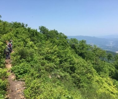Hikers on a green mountain ridge trail with valley views near Juvankan in Nagano Chūbu