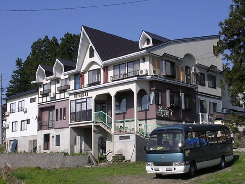 Exterior with shuttle bus Juvankan Chubu Nagano Front facade of Juvankan ryokan with parked shuttle bus and grassy foreground in Nagano
