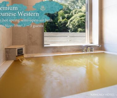 Indoor onsen bath with stone tub and large window overlooking forested hillside at KAMENOI HOTEL Arima in Hyōgo
