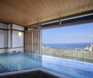 Indoor onsen bath with glass wall and coastal view at KAMENOI HOTEL Atami Annex in Shizuoka, Chūbu, Japan