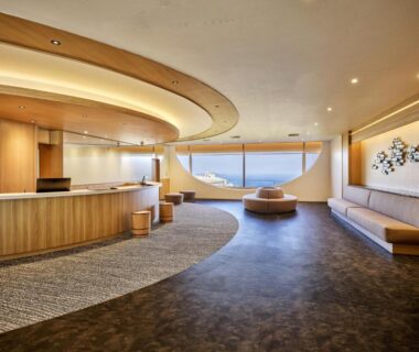 Curved lobby with wooden reception desk and seating at KAMENOI HOTEL Atami Annex Shizuoka overlooking coastal water