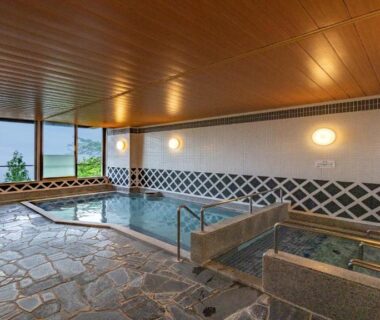 Indoor onsen bath with stone floor and wooden ceiling at KAMENOI HOTEL Atami Annex, Shizuoka, Chūbu