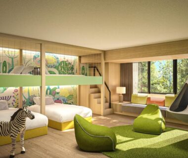 Bright family room with bunk beds, twin beds, green seating, play tent and window showing greenery outside