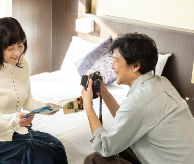 Couple on bed, man holding camera, KAMENOI HOTEL Ichinoseki, Iwate, Tōhoku