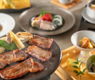Grilled meat slices with assorted Japanese side dishes in a ryokan dinner setting at KAMENOI HOTEL Ichinoseki, Iwate